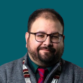 Headshot of Aaron Leggett, wearing glasses, a gray sweater, green shirt, red striped tie and beaded necklace, against a teal background.