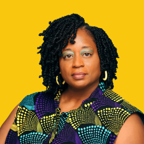 Headshot of Amanda Misiko Andere, looking at the camera with a neutral expression, with shoulder-length black twists, wearing gold hoop earrings and a colorful patterned top against a dandelion-yellow background.