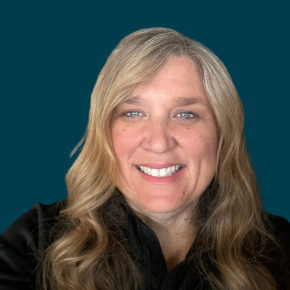 Headshot of Amber Finley, smiling, with long wavy blonde hair, wearing a black top against a dark ocean-blue background.