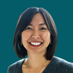 Headshot of Cleo Tung, smiling with shoulder-length dark hair and wearing small hoop earrings and a dark gray top, against a teal background.