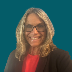 Headshot of Jessica Hunter, smiling, with shoulder-length blonde hair and glasses, wearing a black blazer over a coral top against a dark ocean-blue background.