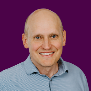 Headshot of Luke Tufts over a plum colored background