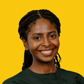 Headshot of Mares Asfaha, smiling, with braided hair pulled back, wearing a dark green top against a dandelion-yellow background.