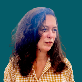 Headshot of Raquel Pfeifer, looking off to the side, with long wavy dark hair, wearing a mustard-and-white checkered shirt against a dark ocean-blue background.