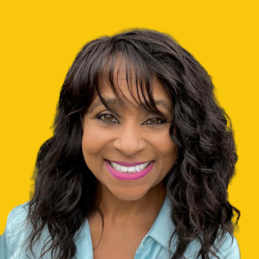 Headshot of Sabrina Smith, smiling, with long wavy black hair and bangs, wearing a light blue collared shirt against a dandelion-yellow background.