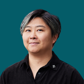 Headshot of Sandee Huang, with short dark hair featuring gray highlights and wearing a black collared shirt, against a teal background.