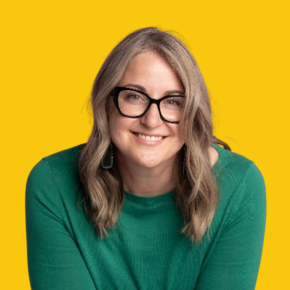 Headshot of Tasha Pineda, smiling, with wavy blonde hair and black glasses, wearing a green sweater and teal earrings against a dandelion-yellow background.