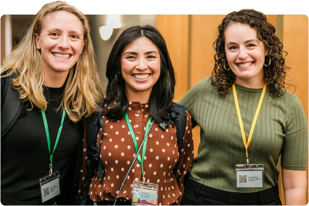 Three Philanthropy Northwest staff members smiling with conference badges conveying a friendly atmosphere.