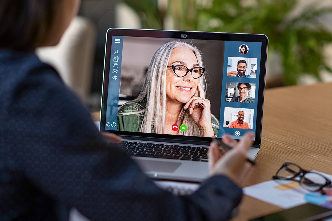 Image of a person looking at a laptop with 5 people on video conference 