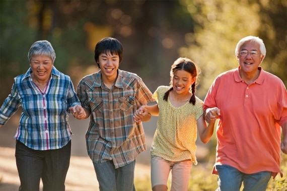 A multi-generational Asian family holds hands while walking in nature