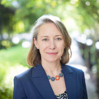 Headshot of Diana Birkett Rakow wearing a dark blue blazer in front of a nature background