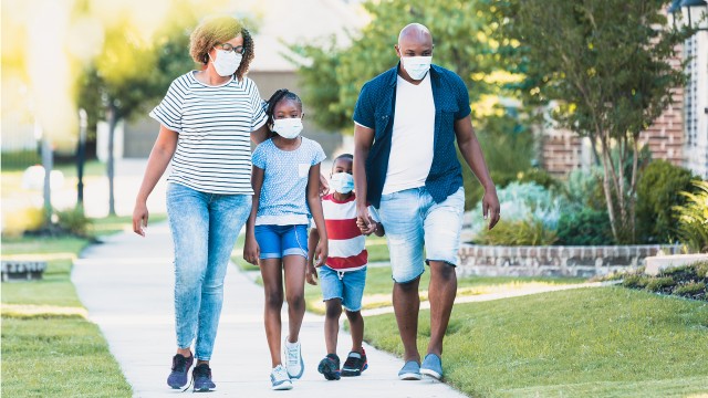 Family wear face masks while walking in their neighborhood during the COVID-19 pandemic.