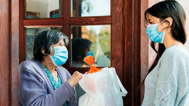 Teenage girl volunteer delivering groceries to a senior woman during the COVID 19 pandemic