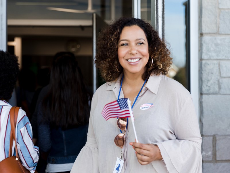 Lady holding an an American flag with an "I voted" sticker