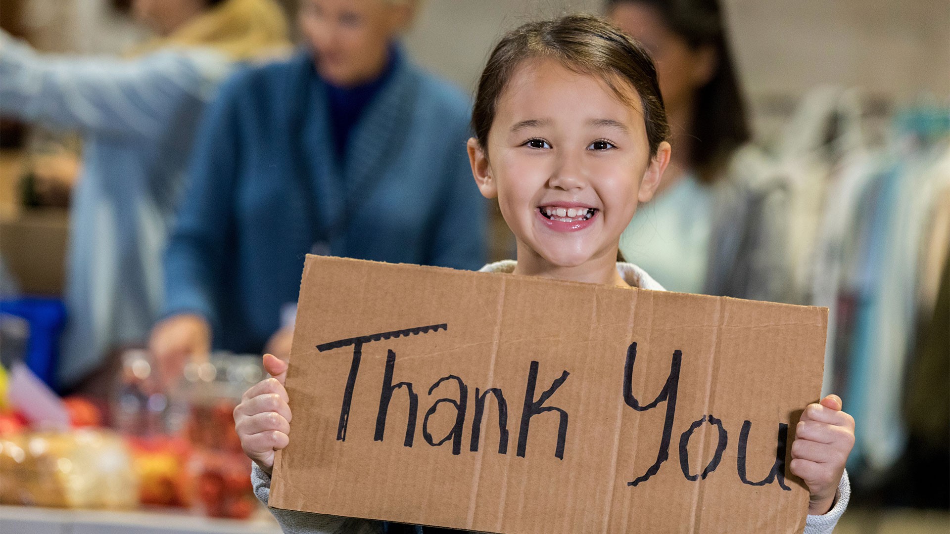Little girl with thank you sign in a food bank