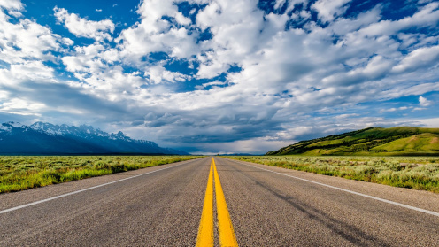 Empty road with cloudy skies and mountains in the distance