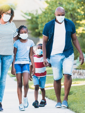 Family wear face masks while walking in their neighborhood during the COVID-19 pandemic.