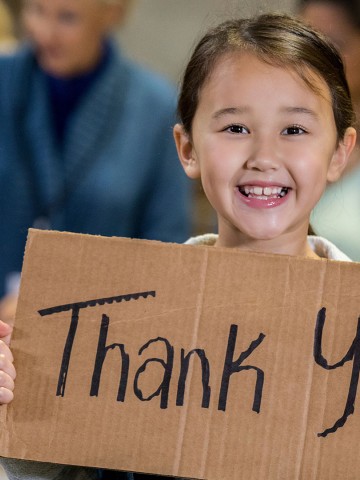 Little girl with thank you sign in a food bank