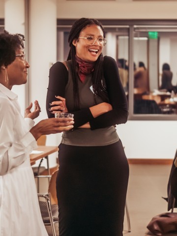 Photo of three black/multi-racial women smiling and talking at the Philanthropy Northwest Voice. Vision. Value. event in 2023