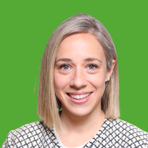 Headshot of Elizabeth Norikane, smiling, with straight blonde bob-length hair, wearing a black-and-white patterned sweater against a grass green background.