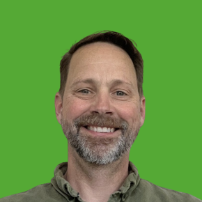 Headshot of Ryan Smith, smiling, over a grass green background