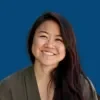 Headshot of Aya Tsuruta, smiling, over a blueberry background