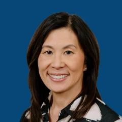 Headshot of Jill Nishi over a blueberry colored background