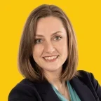 Headshot of Amy Clark, smiling, with shoulder-length light brown hair, wearing a navy blazer over a teal blouse against a dandelion-yellow background.