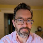 Headshot of Remy Trupin, in a pink button down shirt and blurred background